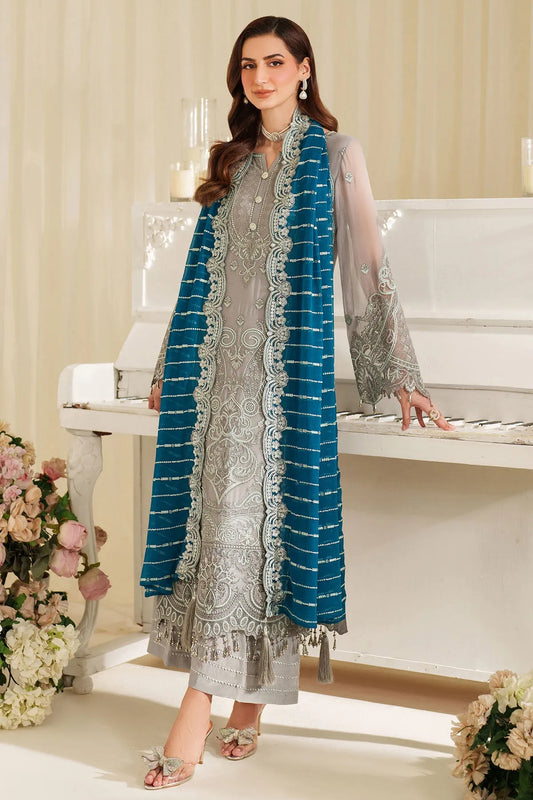 Woman in a gray dress with a blue scarf standing in a decorated room.