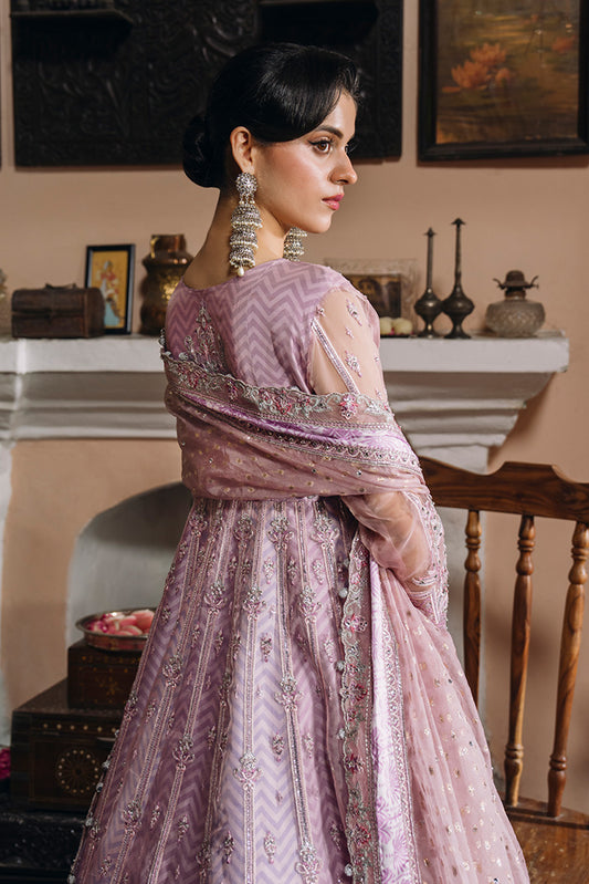 Back view of a model wearing a soft lilac-pink Nikkah dress with intricate silver embroidery, sheer embellished sleeves, a flowing embroidered dupatta, and a detailed flared skirt.