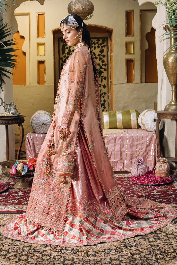 Side view of a peach pink Nikkah dress with intricate embroidery, embellished sheer dupatta, flared hem and a matching embroidered potli bag.