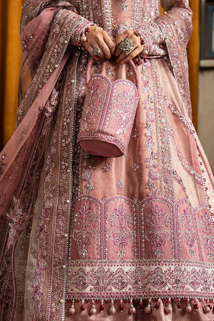 Close-up of a dusty rose Nikkah dress featuring intricate silver and pink embroidery, embellished borders, hanging bead details, and a matching embroidered potli bag.