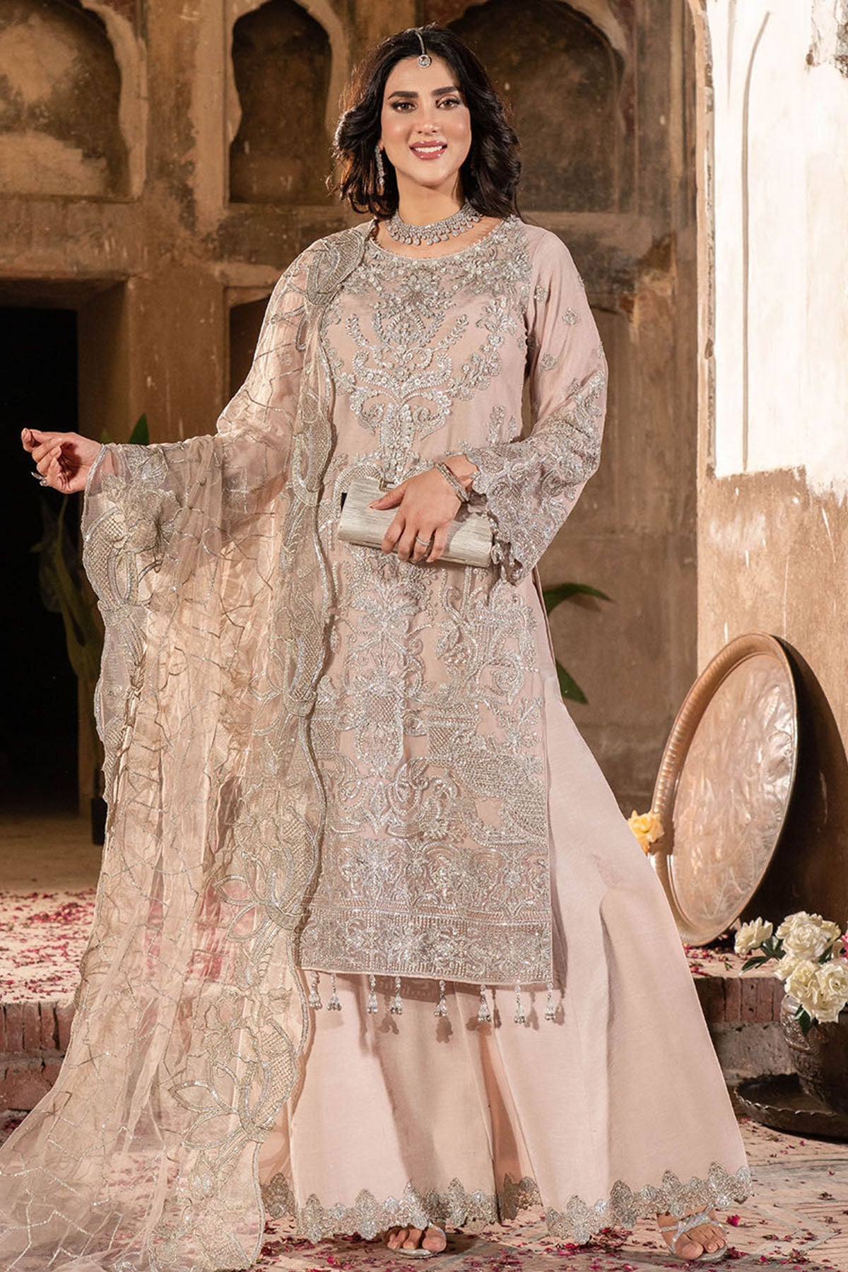 Woman in a traditional embroidered outfit standing in an ornate indoor setting.