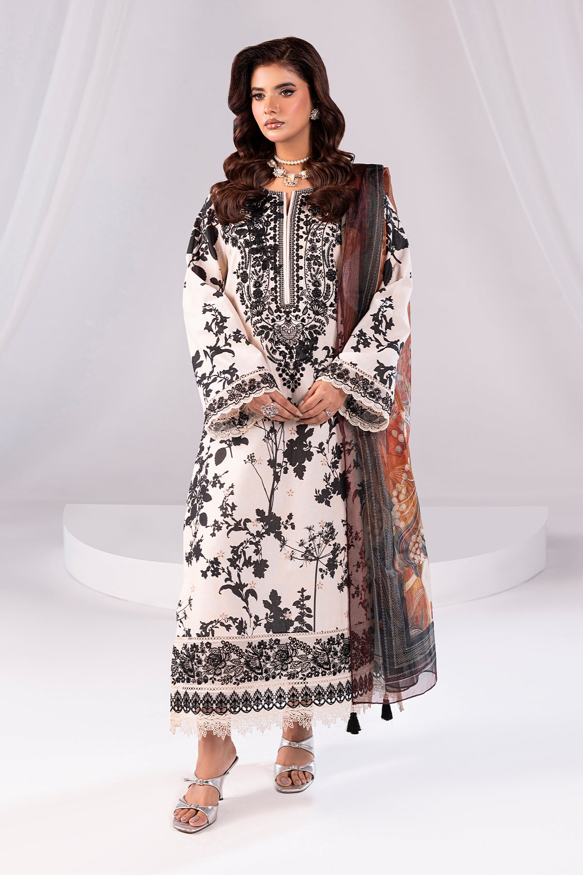 Woman wearing a black and white floral dress with a sheer dupatta on a white background